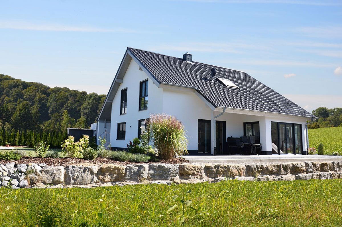 Weißes Massivhaus mit schwarzem Dach